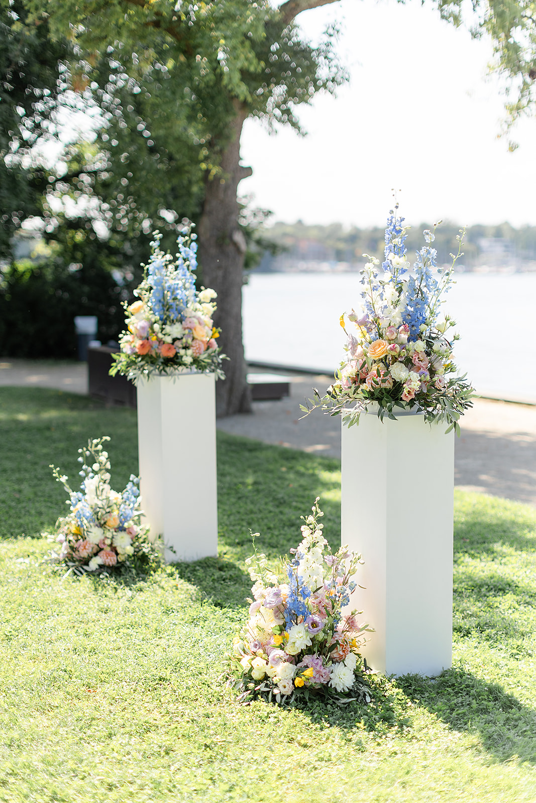 Florale Dekoration am Wasser: bunte Blumenarrangements auf weißen Säulen