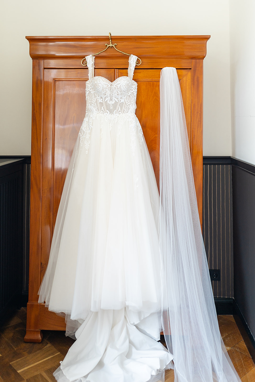 Hochzeitskleid mit Spitzenärmeln und Schleier an einem Schrank