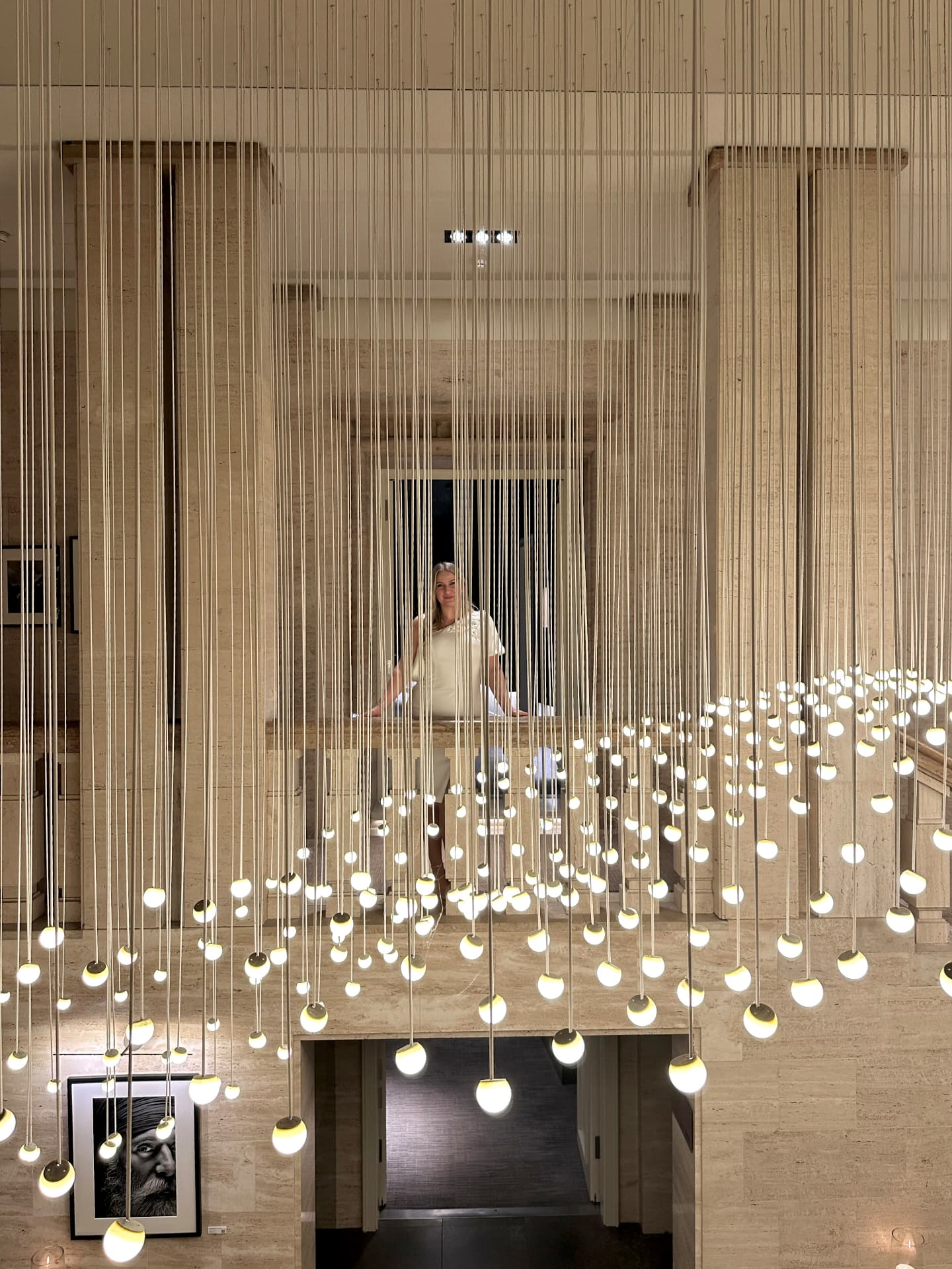 Dominique in elegantem weißen Kleid in stilvollem Interieur mit hängenden Lichtern